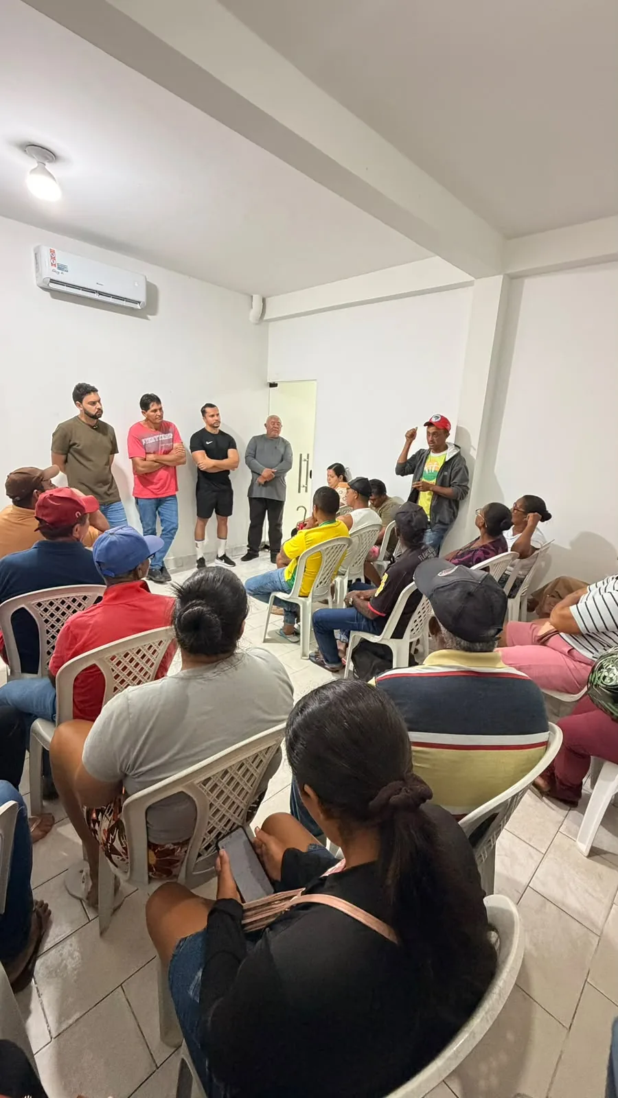 Grupo reunido enquanto participante fala durante encontro comunitário